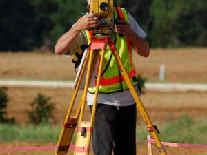 Land surveyor performing a topographic survey on undeveloped land for future homesite planning in Lehi, Utah.